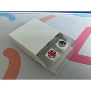 Arrow keycaps in a clear plastic container, featuring a white background with red and black designs, inside a sleek white box.