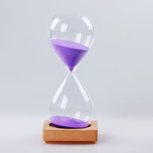 A sand timer with a clear glass hourglass and purple sand, featuring a wooden base.