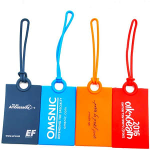 A set of four silicone luggage tags in blue, orange, red, and navy, featuring different logos and branding.