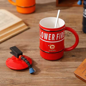 A red mug shaped like a fire extinguisher with a black lid and a straw, featuring a logo.