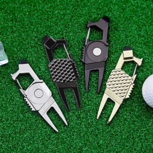 A collection of four 7-in-1 golf tools in silver, black, and gold, displayed on green turf with a golf ball nearby.