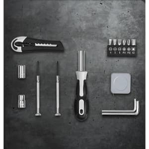 A set of metallic and black tools, including screwdrivers, a utility knife, and various bits on a textured surface.