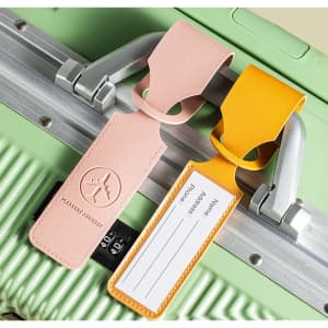 A pink and yellow leather luggage tag attached to a green suitcase, featuring a logo and space for personal information.