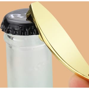 A sleek gold bottle opener with a curved design, held above a black bottle cap.