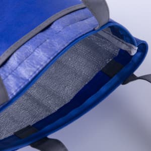 A blue lunch cooler tote with an insulated silver interior and grey handles, featuring a zip closure.
