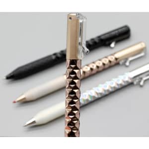 A Crinkle Grip Pen with a textured rose gold grip, alongside black, white, and silver pens, all featuring a clip.
