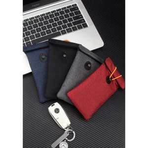 A collection of Faraday Bags in navy, black, grey, and red, beside a car key, set on a laptop background.