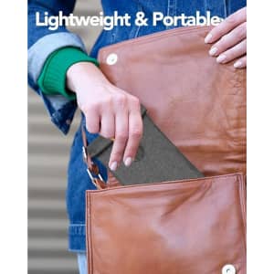 A grey Faraday bag is being placed into a brown leather bag. The background features a denim jacket.