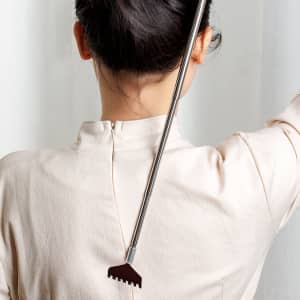 An extendable back scratcher with a metallic handle and a grey claw design, resting on a person's back.