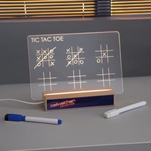 A light-up tic-tac-toe game on a wooden base, featuring white graphics and two markers. It has a logo on the base.