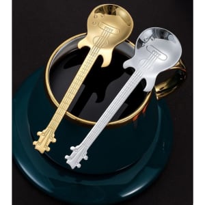 A gold and silver guitar-shaped spoon resting on a dark green plate beside a black cup.