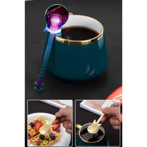A guitar-shaped spoon in rainbow colours rests on the rim of a teal mug, alongside a plate of waffles and fruit.