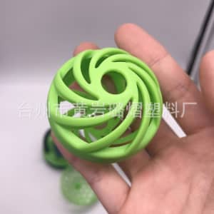 A green silicone ball with a spiral design, held in a hand, featuring an open structure.