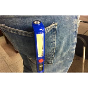 A blue Cob Work Light is clipped onto the back pocket of a pair of denim jeans. The light features a clear lens.