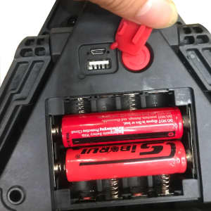 A multifunctional car tool with a red body, displaying battery compartments and charging ports. It features a logo.