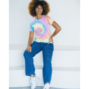 A tie-dye adult T-shirt in pastel colours, featuring a spiral pattern, worn with casual blue jeans and white sneakers.