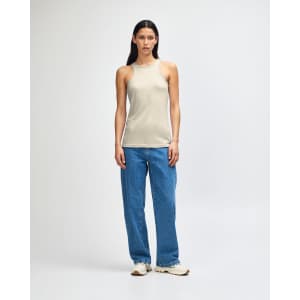A light beige women's racerneck tank top, paired with loose-fitting denim jeans and white sneakers, featuring a logo.