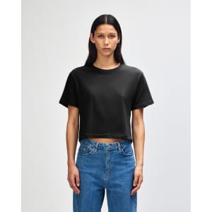 A black women's boxy t-shirt displayed on a model, featuring a relaxed fit and short sleeves.