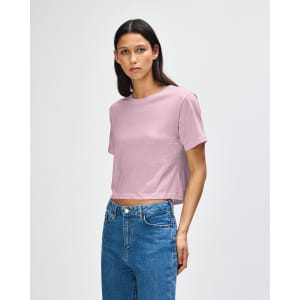 A pink women's boxy t-shirt with a relaxed fit, featuring a logo, styled with denim jeans.