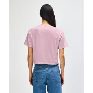 A back view of a pink boxy t-shirt with short sleeves, paired with light blue denim jeans. The shirt features a logo.
