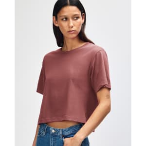 A model wearing a boxy, short-sleeved fine jersey T-shirt in a muted rose colour, paired with light denim shorts.