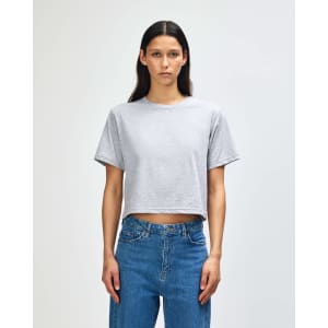 A grey women's boxy t-shirt with short sleeves, displayed on a model. The shirt has a logo.