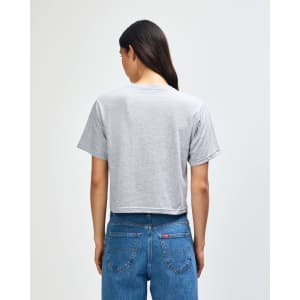 A women’s grey boxy t-shirt with a crew neck, displayed from the back, paired with blue jeans.