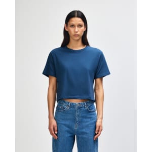 A navy women's fine jersey boxy T-shirt featured on a model, paired with light blue jeans. The shirt has a logo.