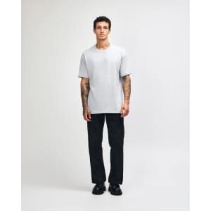 A heavyweight cotton unisex T-shirt in light grey, worn by a person with olive green trousers and sneakers.