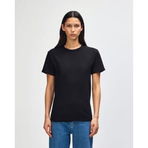 A heavyweight cotton unisex T-shirt in black displayed on a model, featuring a simple design and short sleeves.