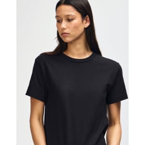 A unisex heavyweight cotton T-shirt in black, featuring a logo, worn by a model with a shaved head.