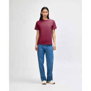 A unisex heavyweight cotton t-shirt in maroon, worn with light blue baggy jeans and black sneakers, featuring a logo.