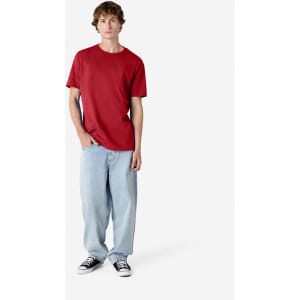 A model wearing a red heavyweight cotton unisex T-shirt paired with light blue jeans and black sneakers.