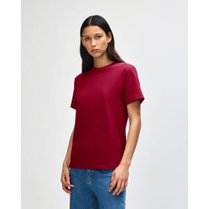 A heavyweight unisex t-shirt in burgundy, featuring a simple design and short sleeves, paired with blue jeans.