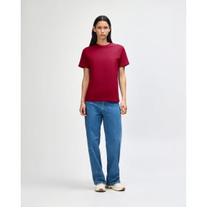 A model wearing a heavyweight cotton unisex T-shirt in burgundy, paired with blue jeans.