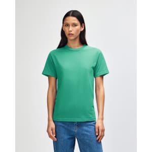 A green heavyweight cotton unisex T-shirt displayed on a model with curly hair, set against a plain background.
