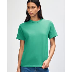 A green heavyweight cotton unisex T-shirt is displayed on a model with curly hair, featuring a simple design and a logo.