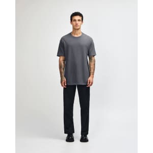 A unisex heavyweight cotton t-shirt in grey, paired with light blue jeans and black sneakers, featuring a logo.