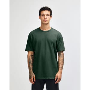 A unisex heavyweight cotton T-shirt in a dark green colour, displayed on a model with curly hair.