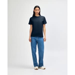 A heavyweight cotton unisex t-shirt in navy blue, displayed on a model wearing blue denim jeans.