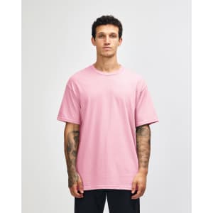 A unisex heavyweight cotton T-shirt in pink, worn by a model, with a simple and casual design.