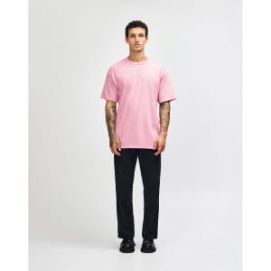 A heavyweight cotton unisex T-shirt in pink, paired with light blue jeans and black sneakers, displayed on a male model.