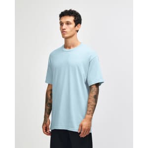 A light blue heavyweight cotton unisex t-shirt on a model, featuring a simple design and a logo.