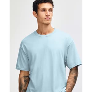 A light blue heavyweight cotton unisex T-shirt displayed on a model with short curly hair. It has a logo.
