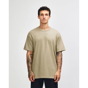 A heavyweight unisex T-shirt in a muted olive green colour, displayed on a model with curly hair.