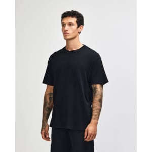 A black unisex garment dyed heavyweight cotton t-shirt displayed on a model, featuring a relaxed fit.