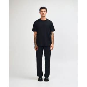 A black unisex heavyweight cotton T-shirt worn with olive green cargo pants, featuring a logo on the shirt.