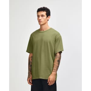 A model wearing an olive green unisex heavyweight cotton T-shirt. The shirt has a relaxed fit and short sleeves.