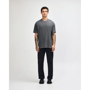 A model wearing a grey heavyweight cotton t-shirt paired with olive green cargo pants. The shirt has a logo.