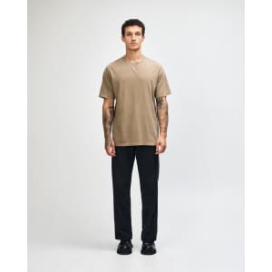 A unisex heavyweight cotton T-shirt in earthy brown, worn with light blue jeans and dark sneakers.